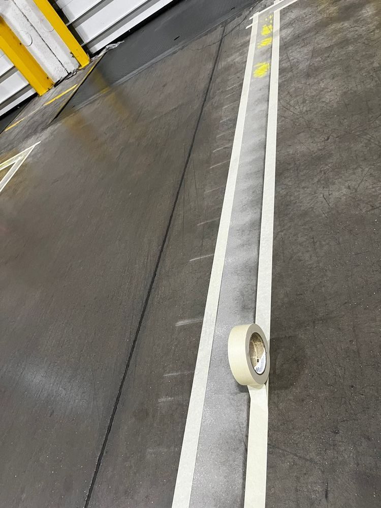 Floor striping in progress — masking tape layout before paint application, PPD Painting warehouse floor marking project