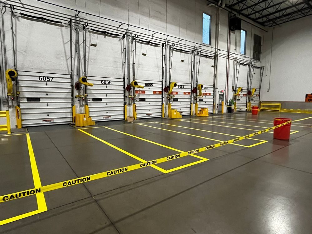 Completed warehouse floor marking at loading dock bays — yellow OSHA safety striping delineating dock staging zones, PPD Painting project