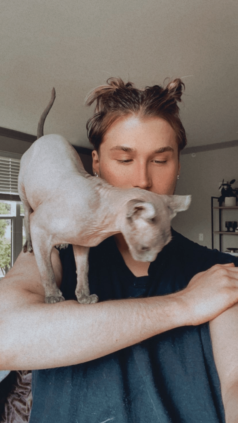 Liam taking a selfie with his hairless cat, Pharaoh, sitting on his shoulder like a parrot.