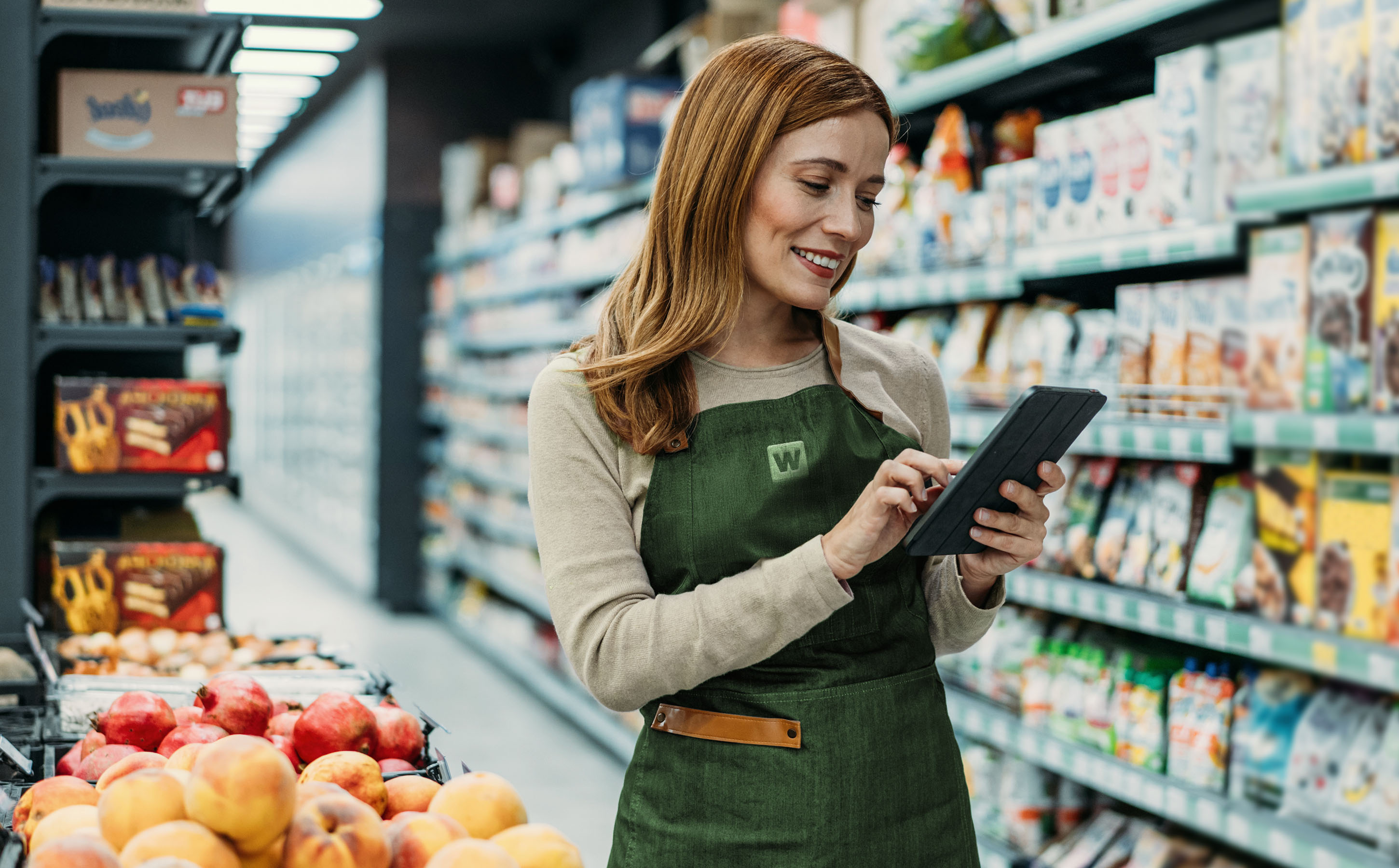 A supermarket employee using the picker app on a tablet to pick and collect groceries for a customer order.