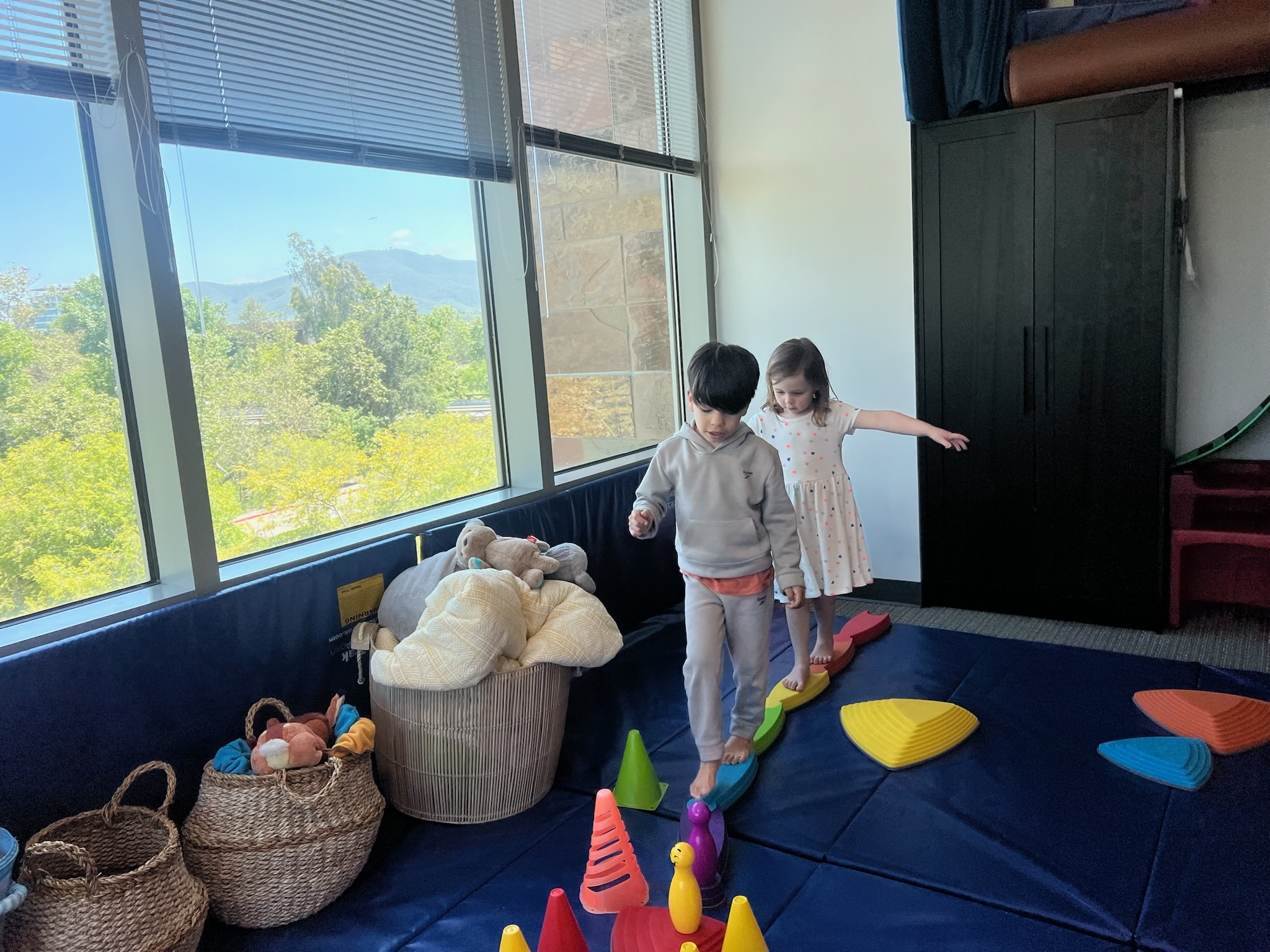 Two children balancing on colorful stepping stones during a speech therapy session at Speech-N-Motion’s San Marcos, California clinic.