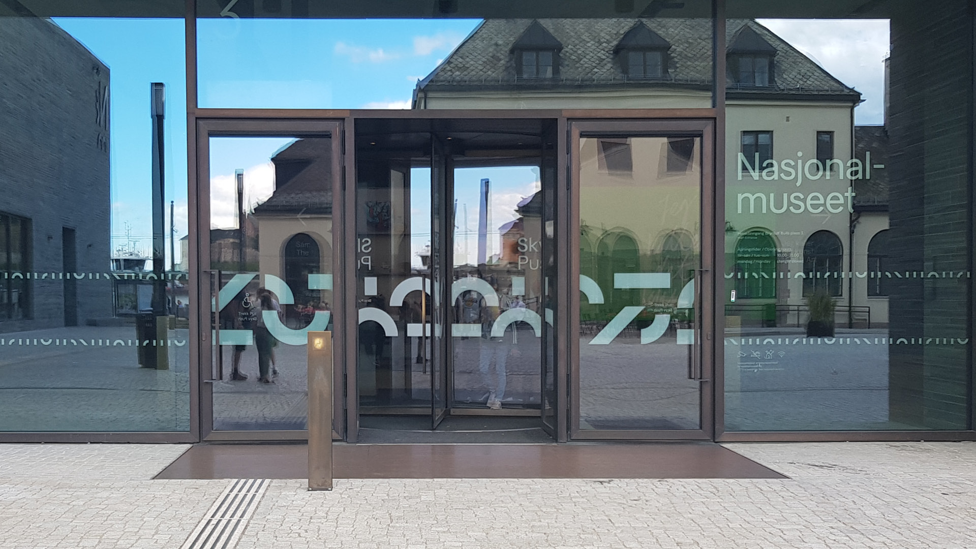 Billede af glasfacade og indgang til Nationalmuseet i Oslo. Der grafiske, hvide logo er blevet brugt til at lave markering på glasset.