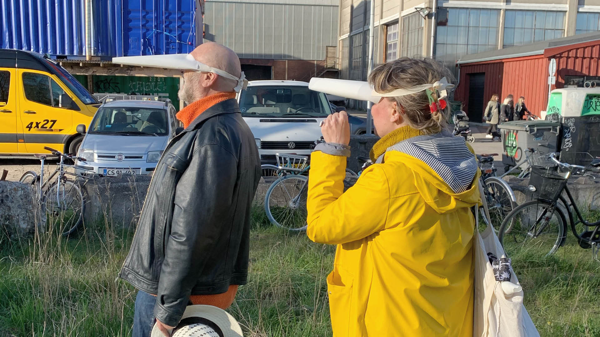 To personer går en tur. De har en maske på formet som et næb, hvor de kun kan se lidt. 