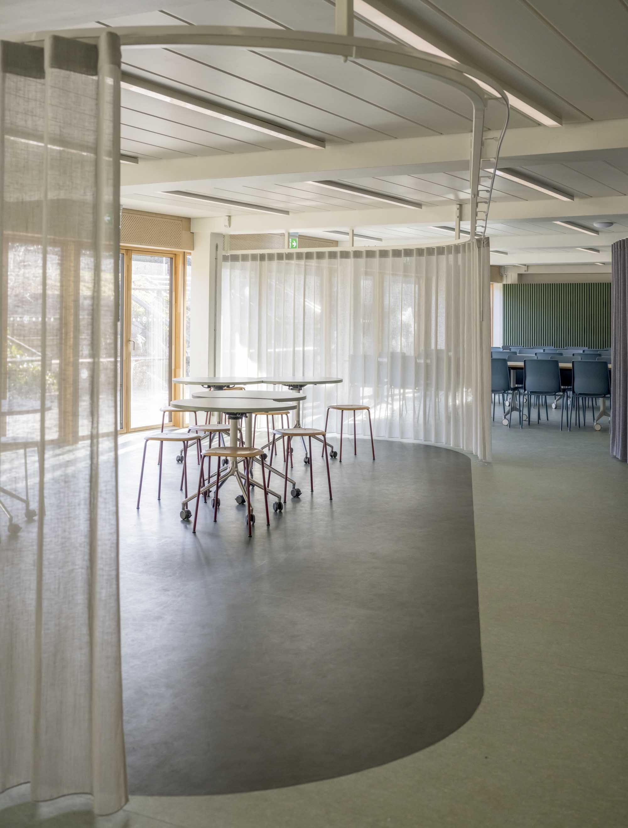 Højformat billede hvor man kan se forskellige sektioner af kantinen, adskildt af gardiner.