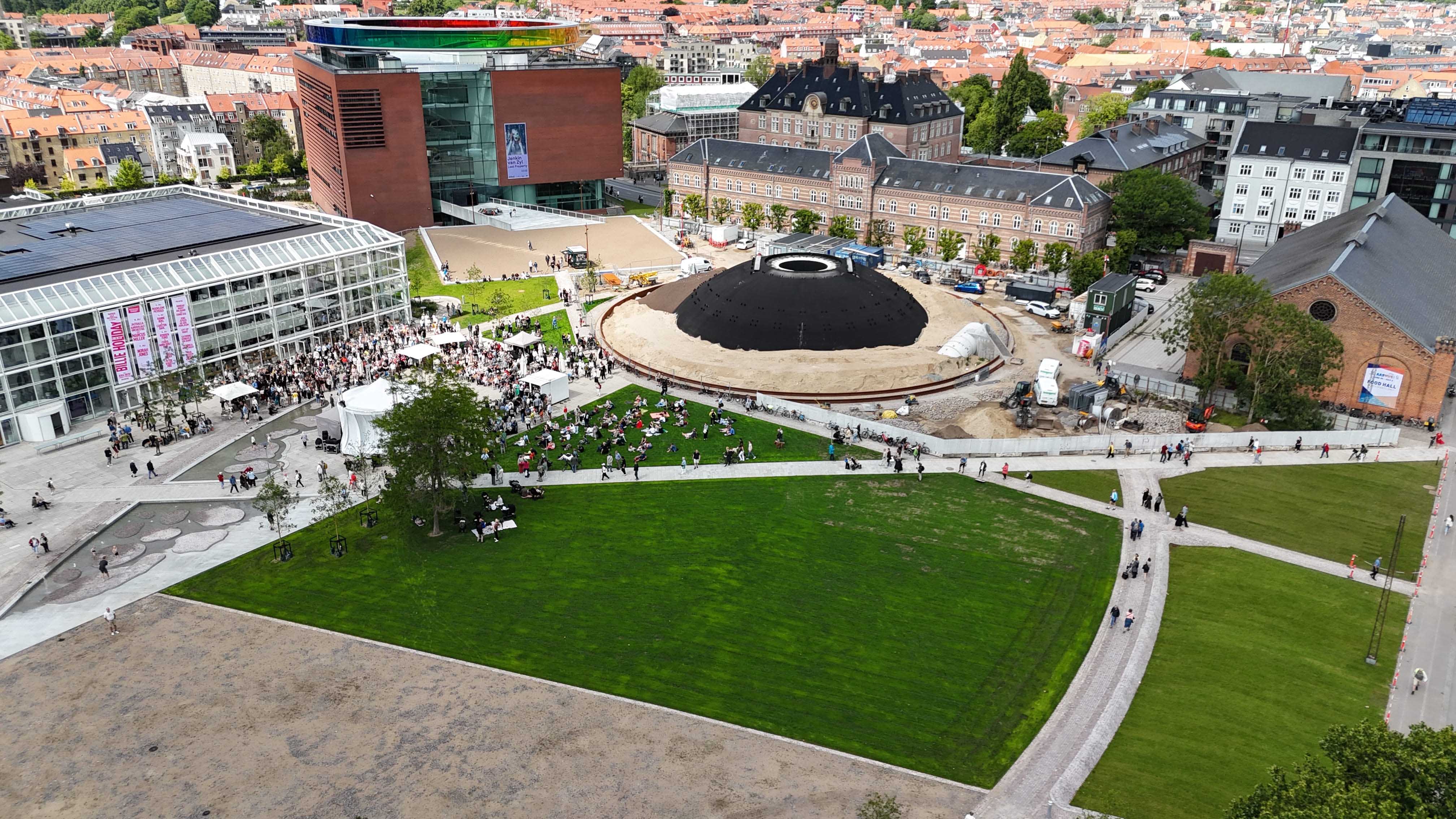 Luftfoto af parken, med stort græsareal og en stop mørk kuppel.