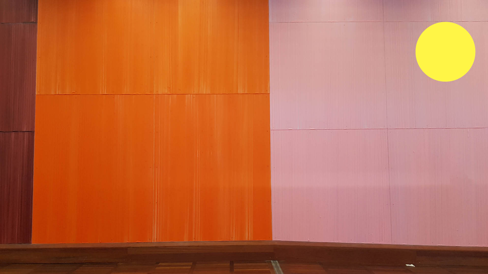 Kig mod væg med maleri med store farvede flader i brun, orange og pink. 