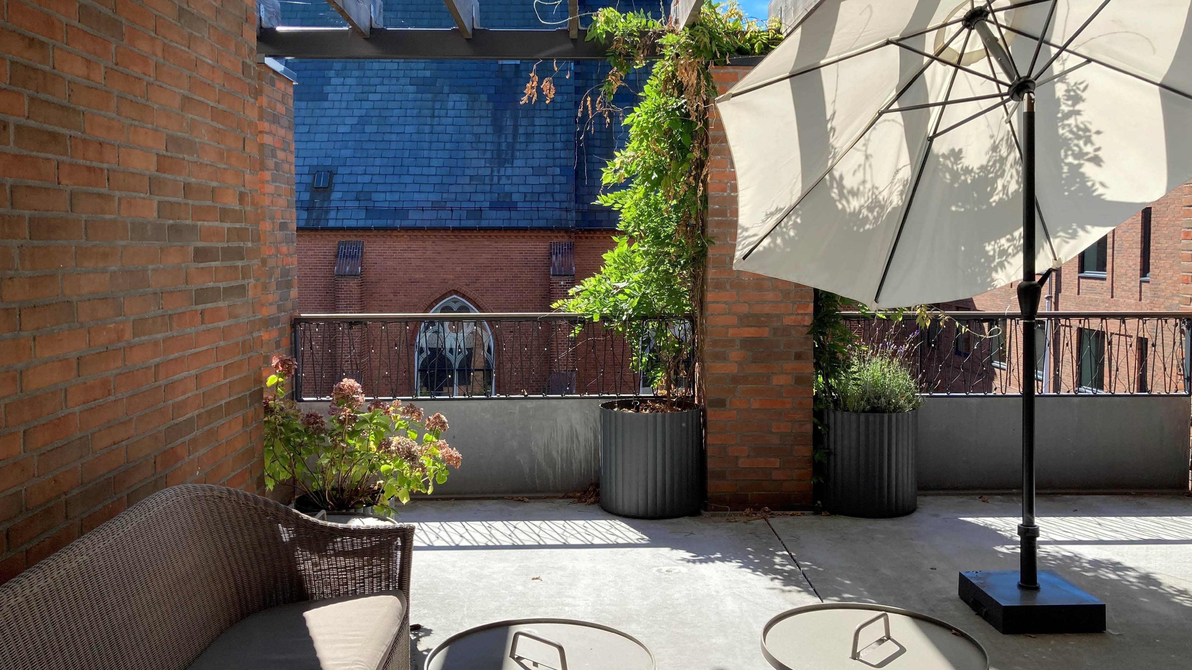 foto hvor solen står ind på tagterrassen, hvor der er sat en parasol op.