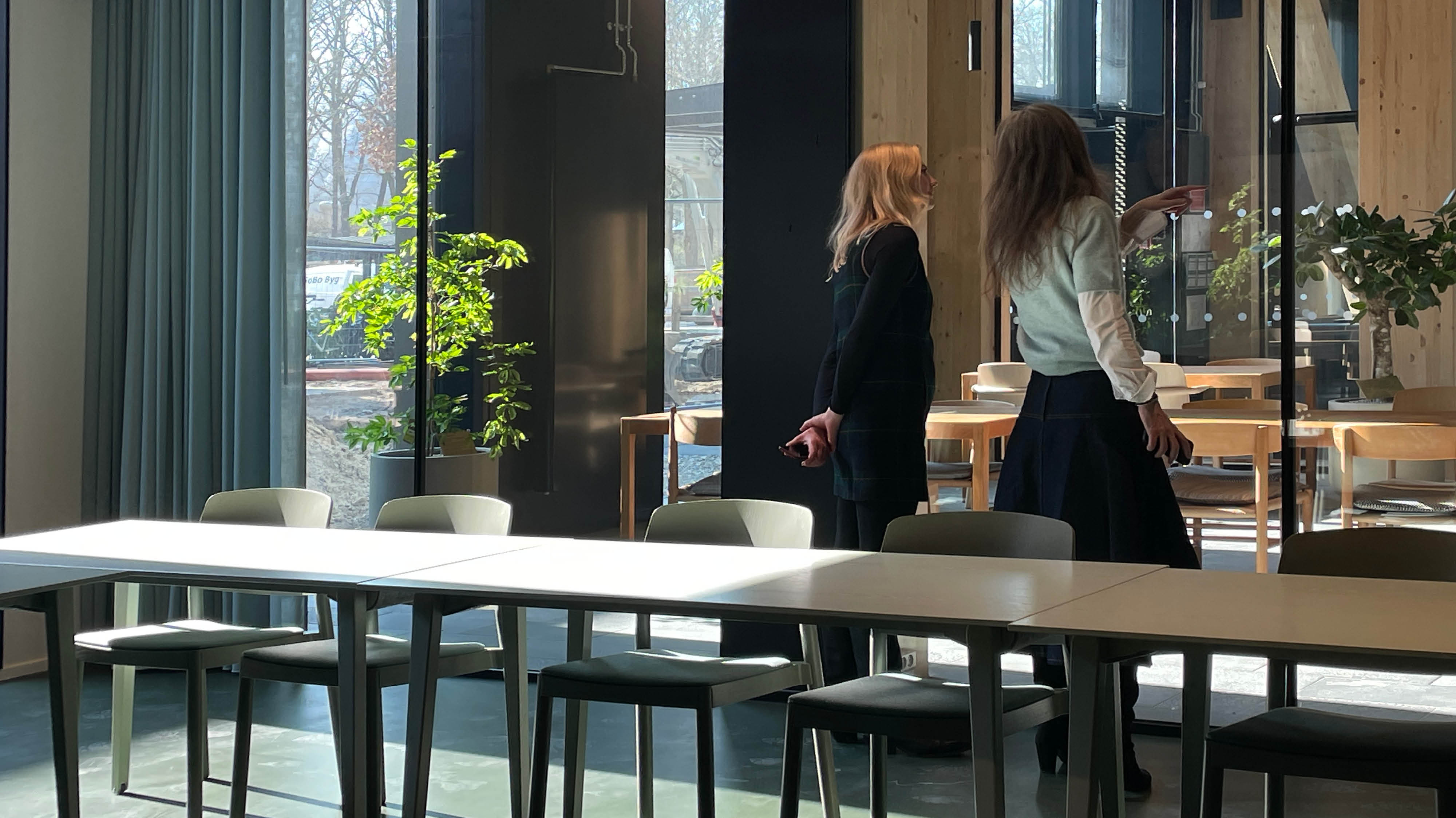 Klasselokale med stort glasparti. To personer står og kigger ud på rummet udenfor klasselokalet.
