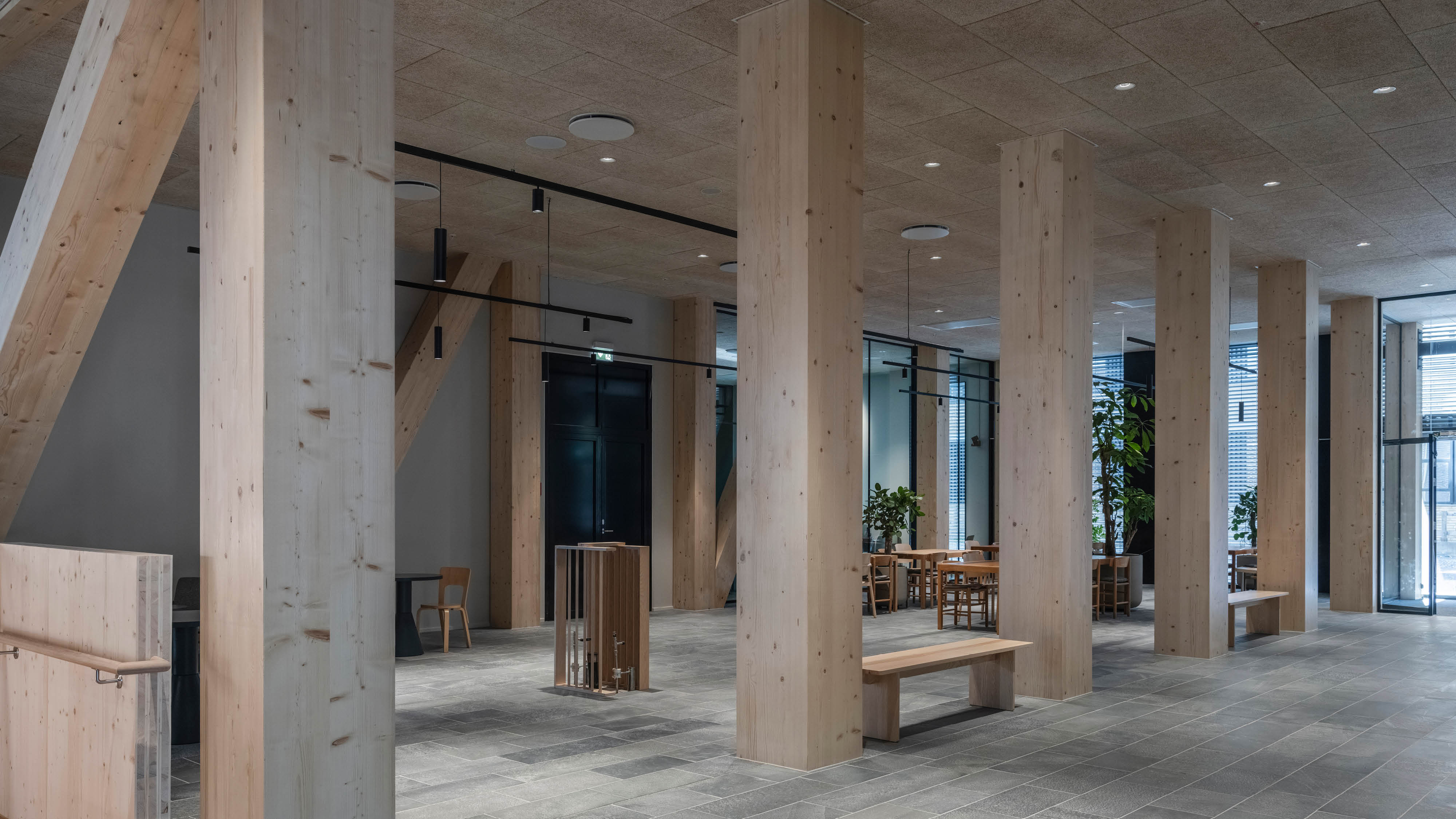 Billede af træsøjler placeret i en lige linje, bag søjlerne er der placeret borde og kaffemaskine.