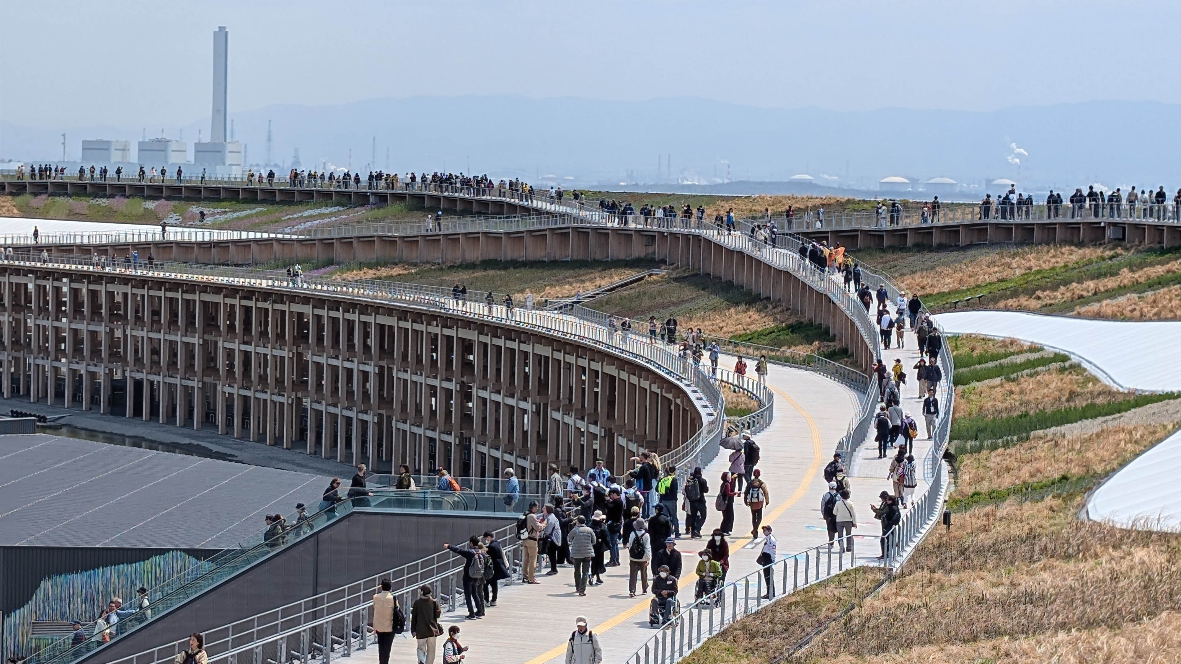 Rulletrappe op til det landskab af stier, som ligger oven på den store ring rundt om hele expo 25-området. Der er en gul ledelinje.