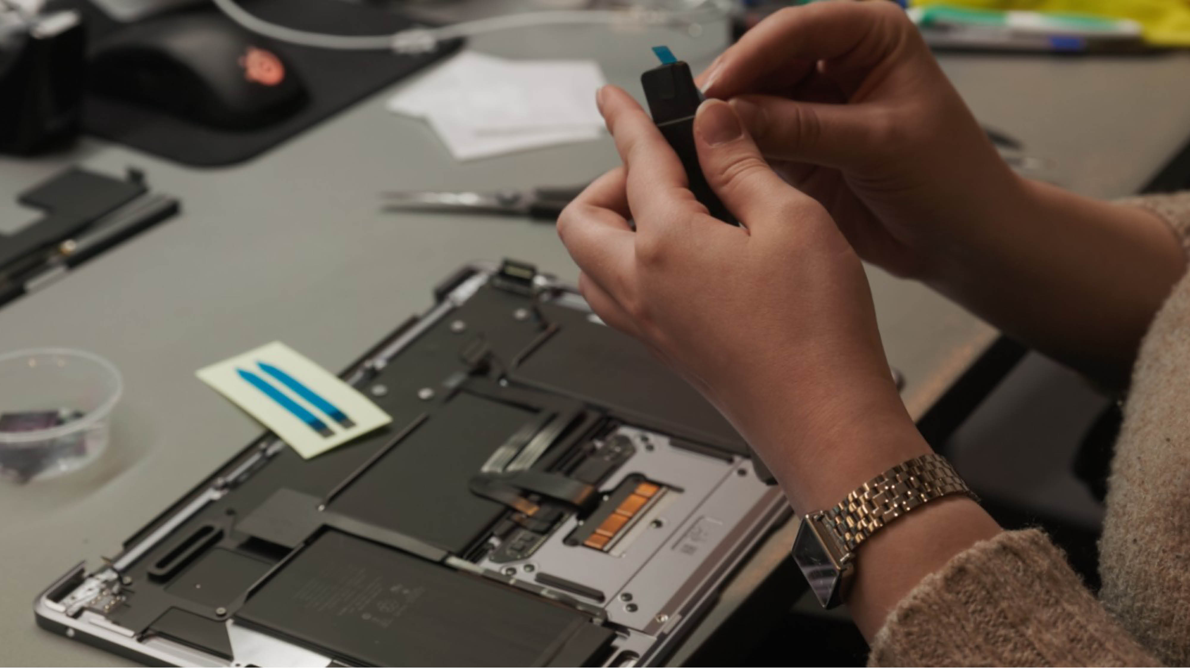 To hænder der sidder med tekniske elektronikdele ved et skrivebord.