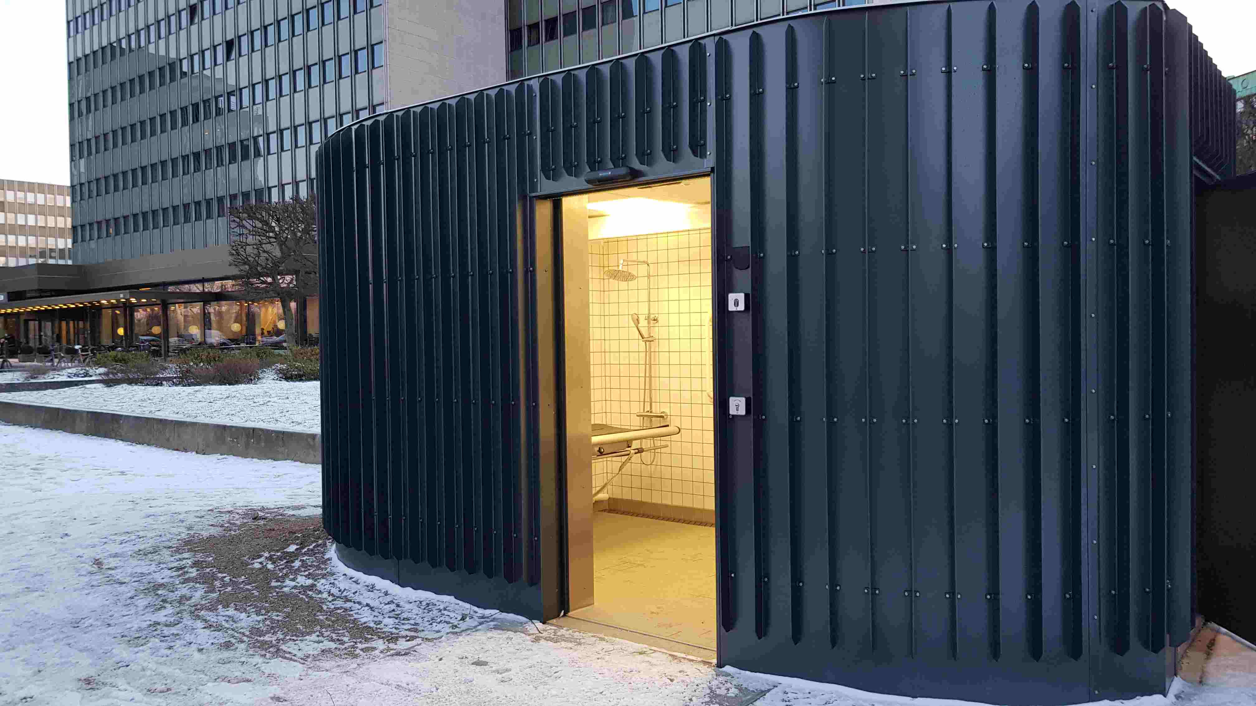 foto af en toiletbygning med åben dør, man kan se en skifteplads.