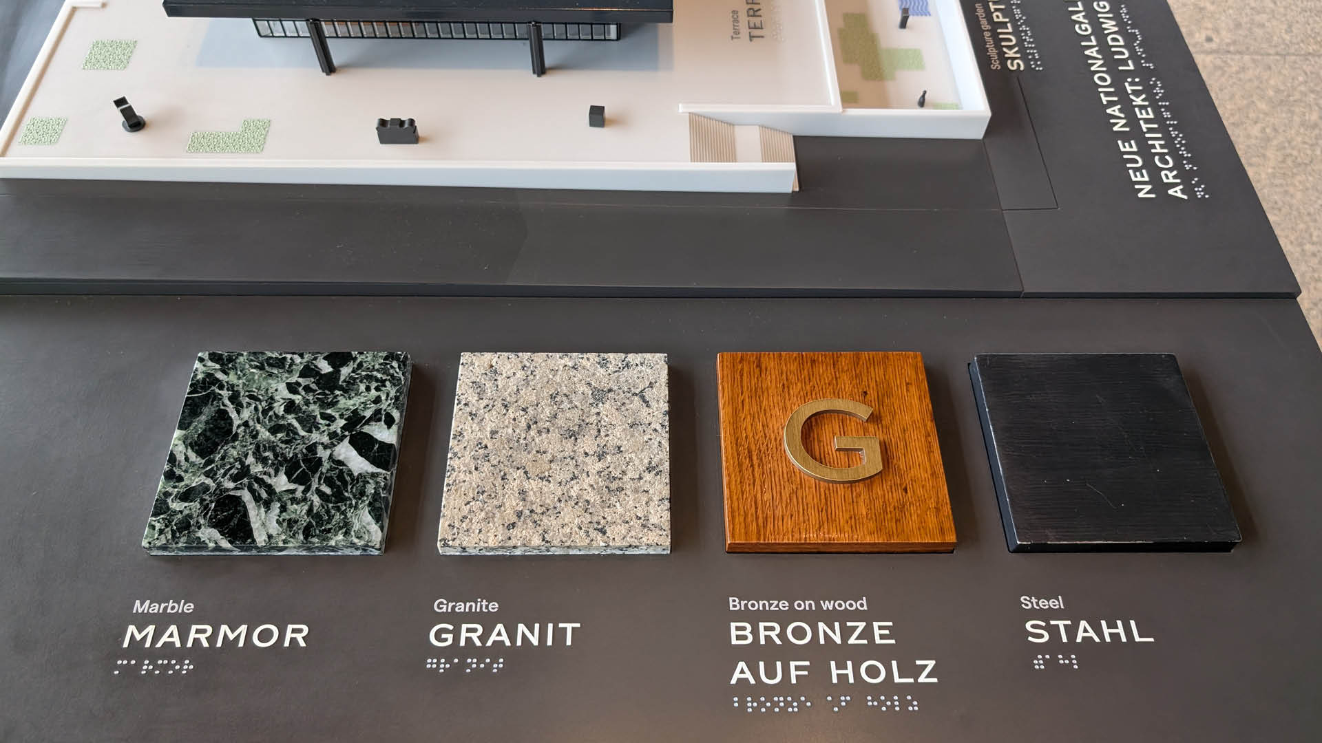 Et foto af en arkitekturmodel af et neues galleri i Berlin med materiale prøver og brailleskrift.