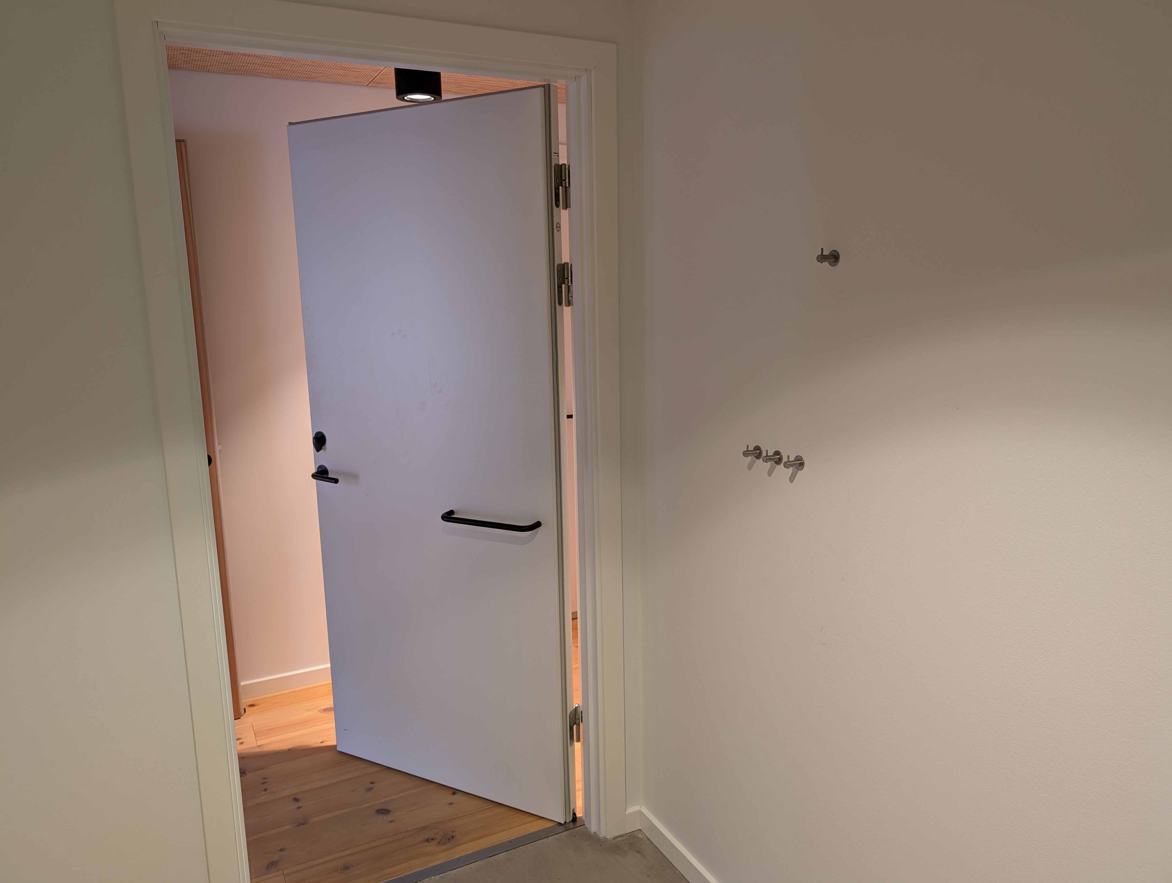 Dør med greb på indersiden av døren, og knager på væggen.