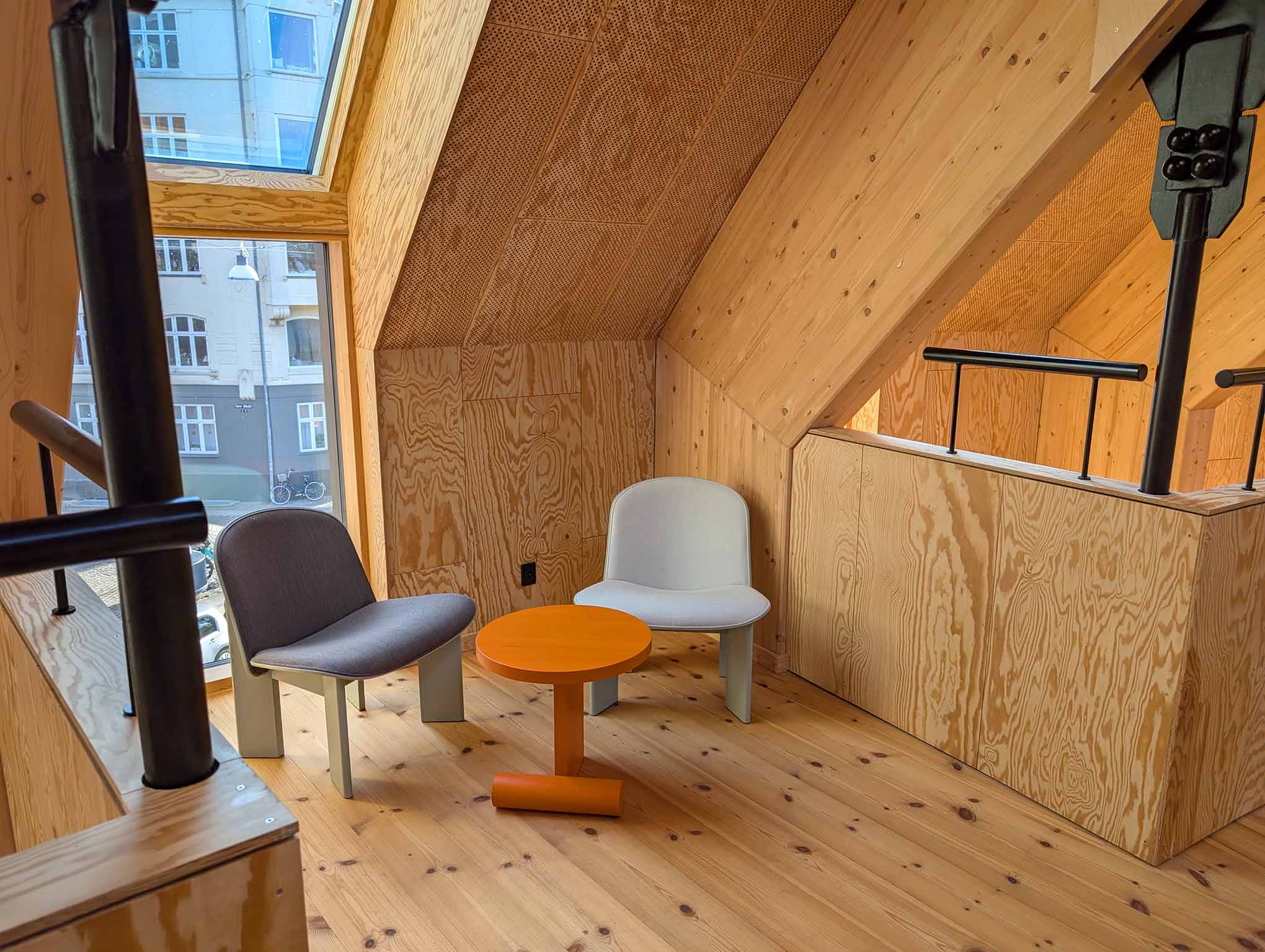  Stole og et bord placeret i en lille stue med et vindue ud mod gaden