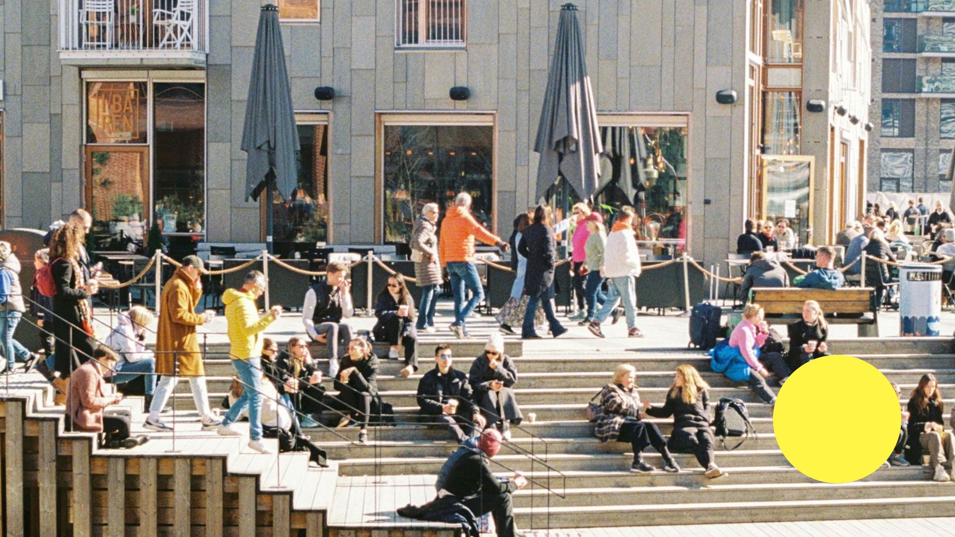 Mennesker i solskin på en siddetrappe ved havnefront i Oslo