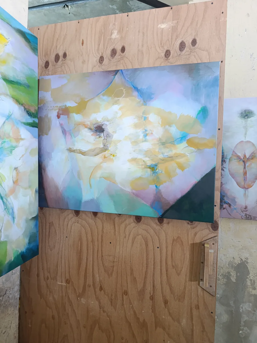 Detail of an abstract painting in yellow, blue and white tones with a reclining figure, mounted on a plywood panel.