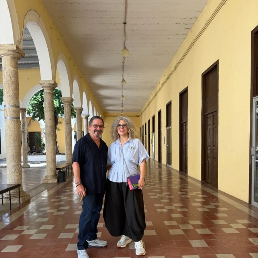 Leonardo Rodríguez and Ivonne Ferrer in a colonial corridor with yellow walls and arches in Mérida.