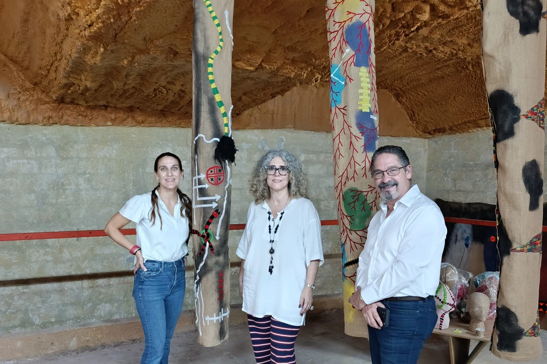 Claribel Calderius (center) with Ivonne Ferrer (left) and Leonardo Rodríguez (right) among the artist's tall embroidered textile works in her Mérida studio.