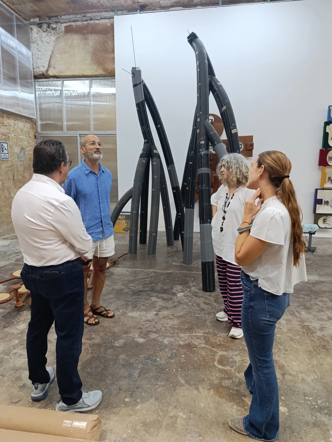 The visitors viewing a large black tubular sculpture in Claribel Calderius's studio.