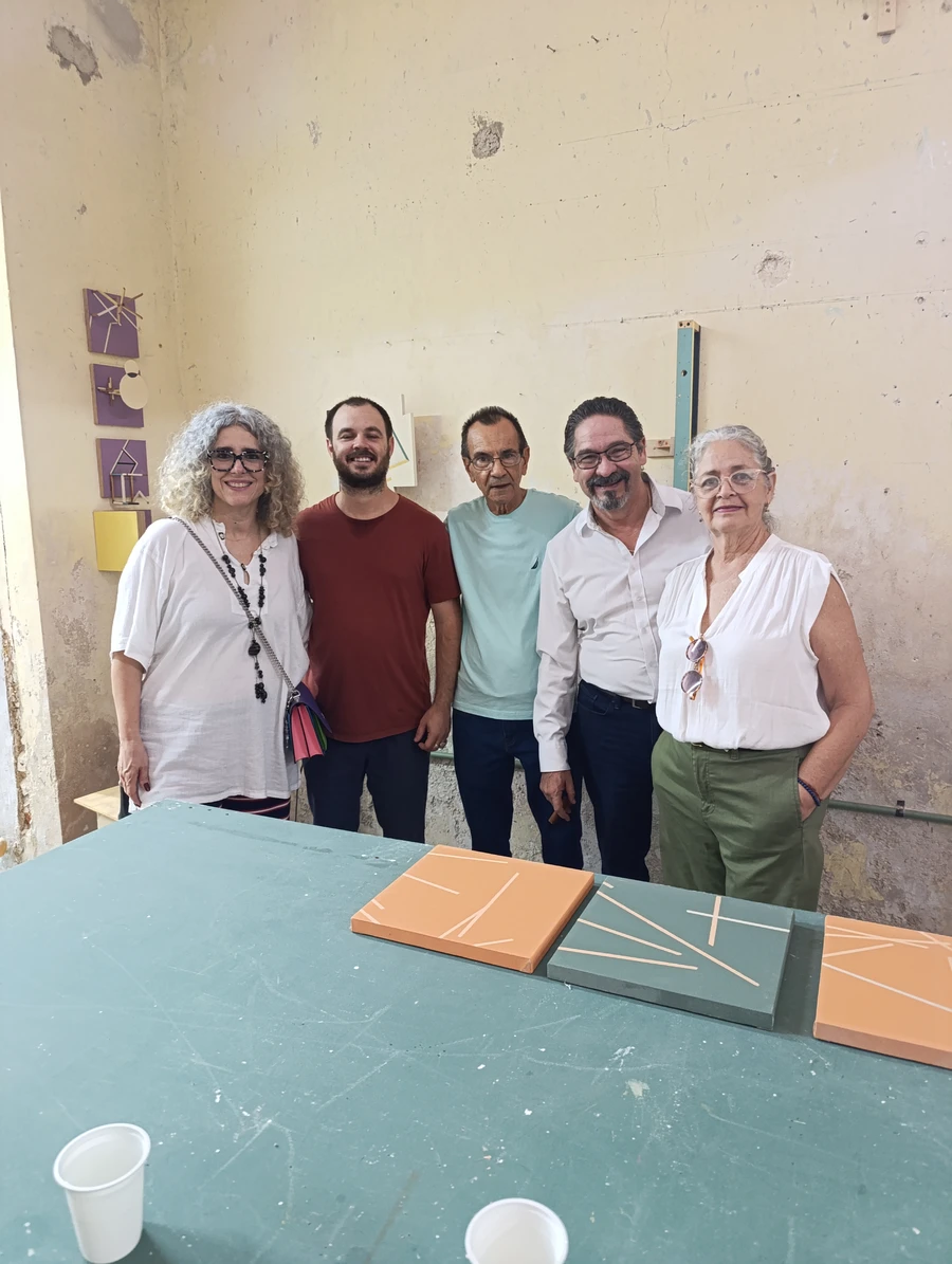 Group of five people posing behind a table displaying minimalist geometric paintings in the studio.