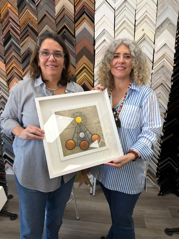 Two women holding the framed artwork by Rosario Verdecia
