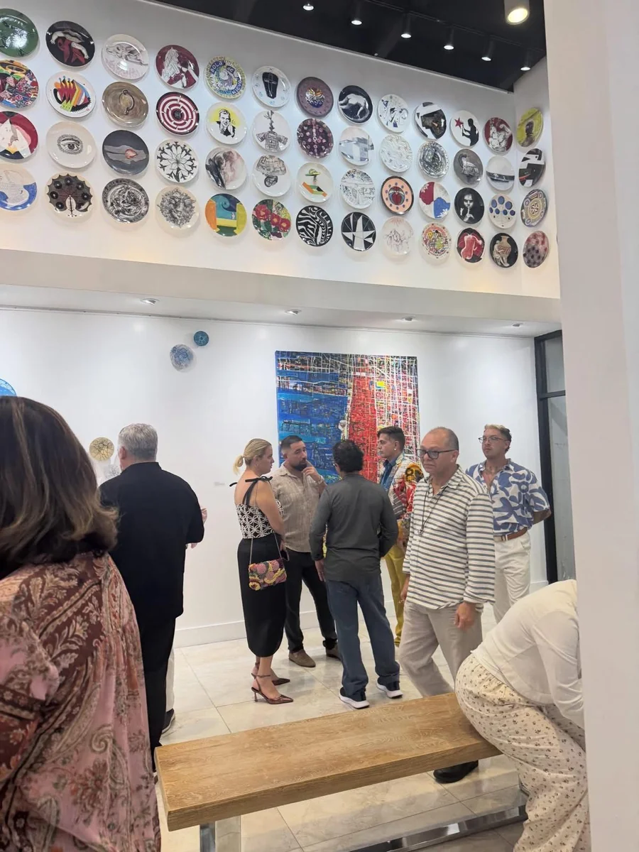 Guests in the main hall during the opening of Beauty as Protest, beneath the wall of ceramic plates.