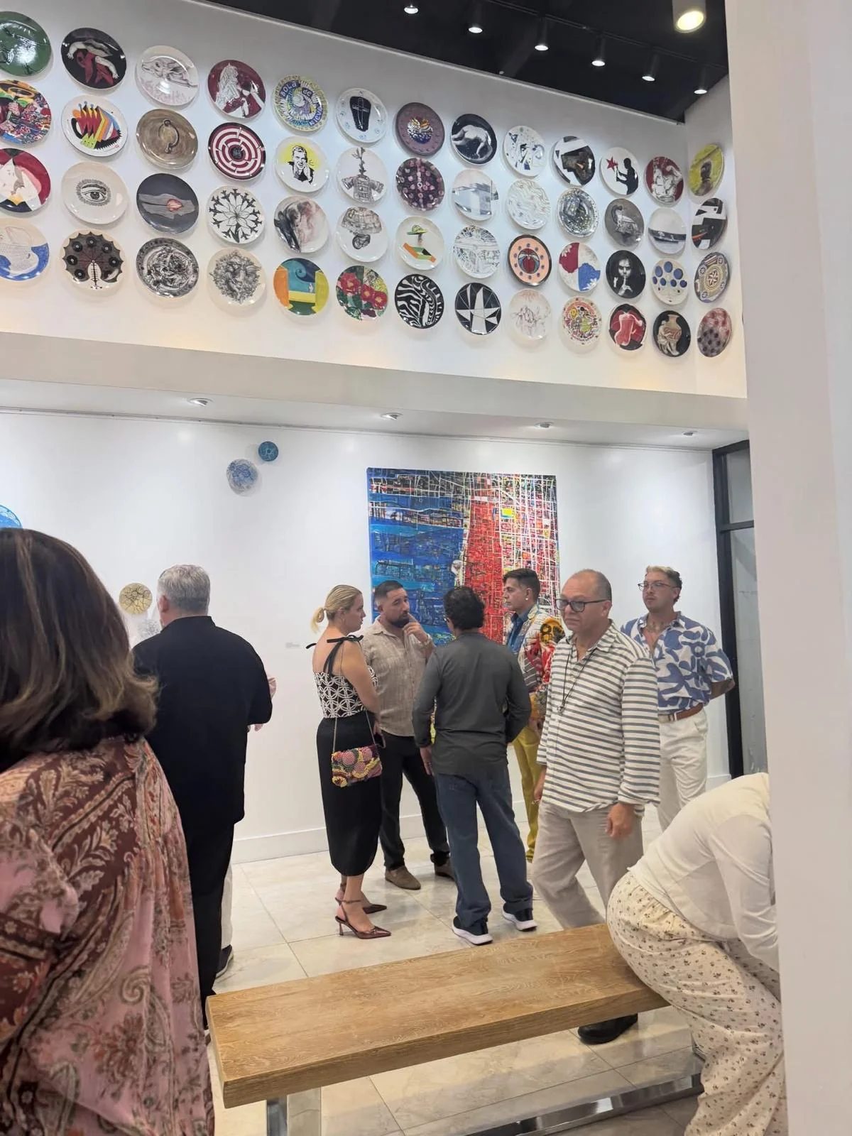 Guests in the main hall during the opening of Beauty as Protest, beneath the wall of ceramic plates.