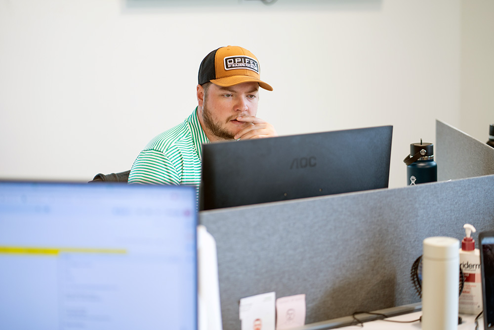A worker is sitting at his computer, looking very intently at the screen