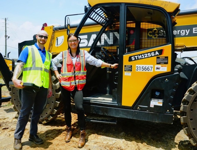 Two of our teammates standing next to a piece of our rental equipment