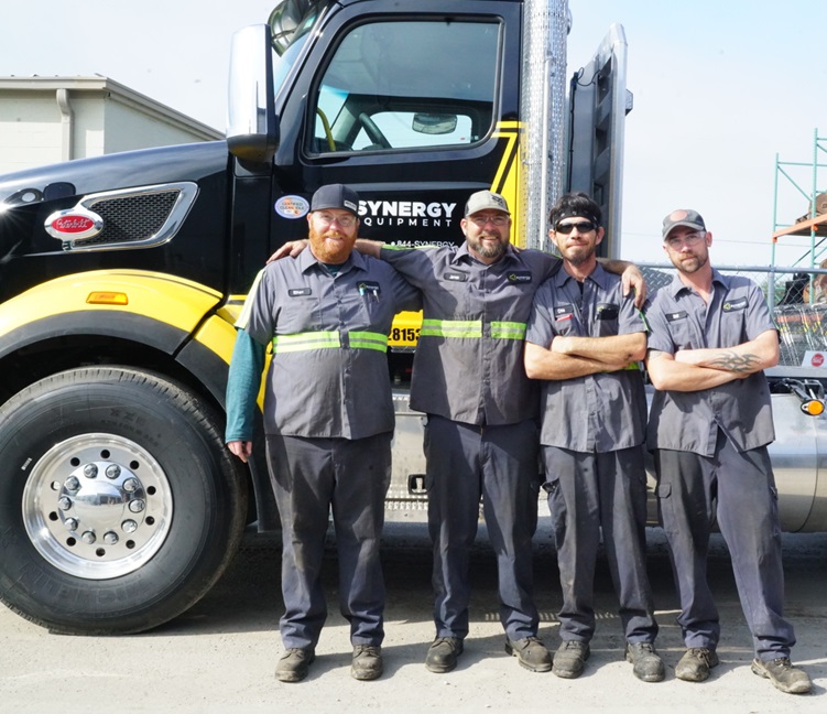 Four of our teammates standing next to one of our delivery trucks