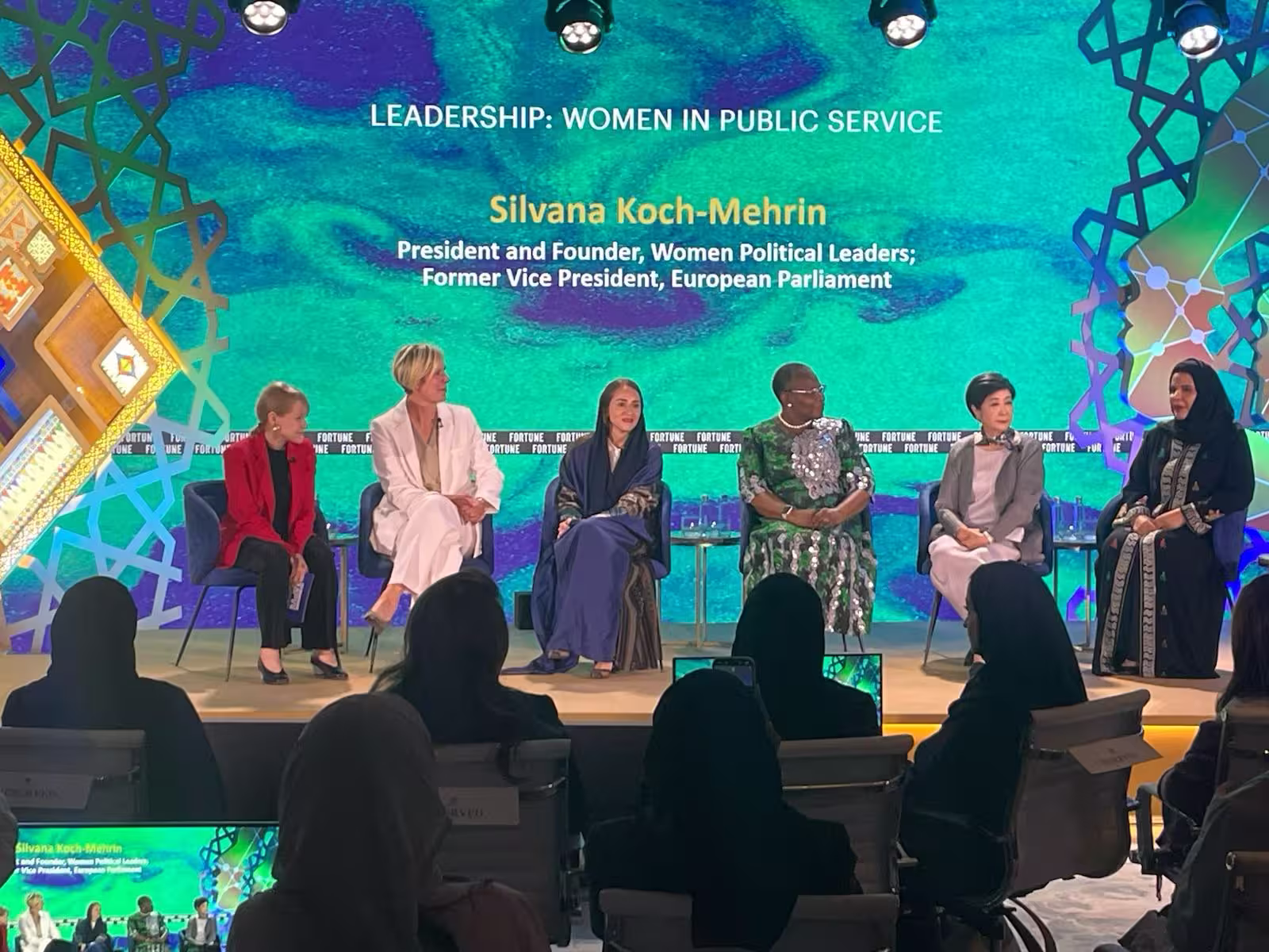 Six women leaders seated on stage for a Fortune panel discussion titled "Leadership: Women in Public Service", with a teal backdrop identifying the speaker as Silvana Koch-Mehrin, President and Founder of Women Political Leaders.