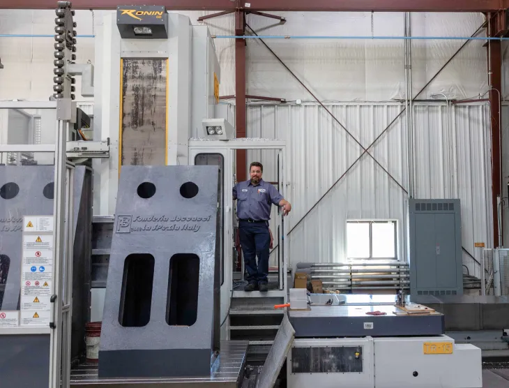 A person standing on platform of large horizontal milling machine.