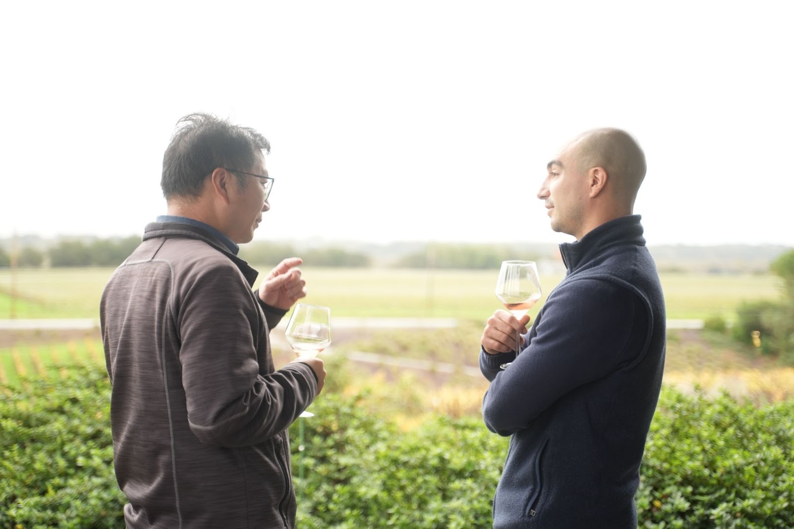 Two attendees conversing on a vineyard terrace with wine glasses in hand during the Better Together 2025 event in Sonoma, hosted by Zaelab in partnership with ServiceNow and Shopify.