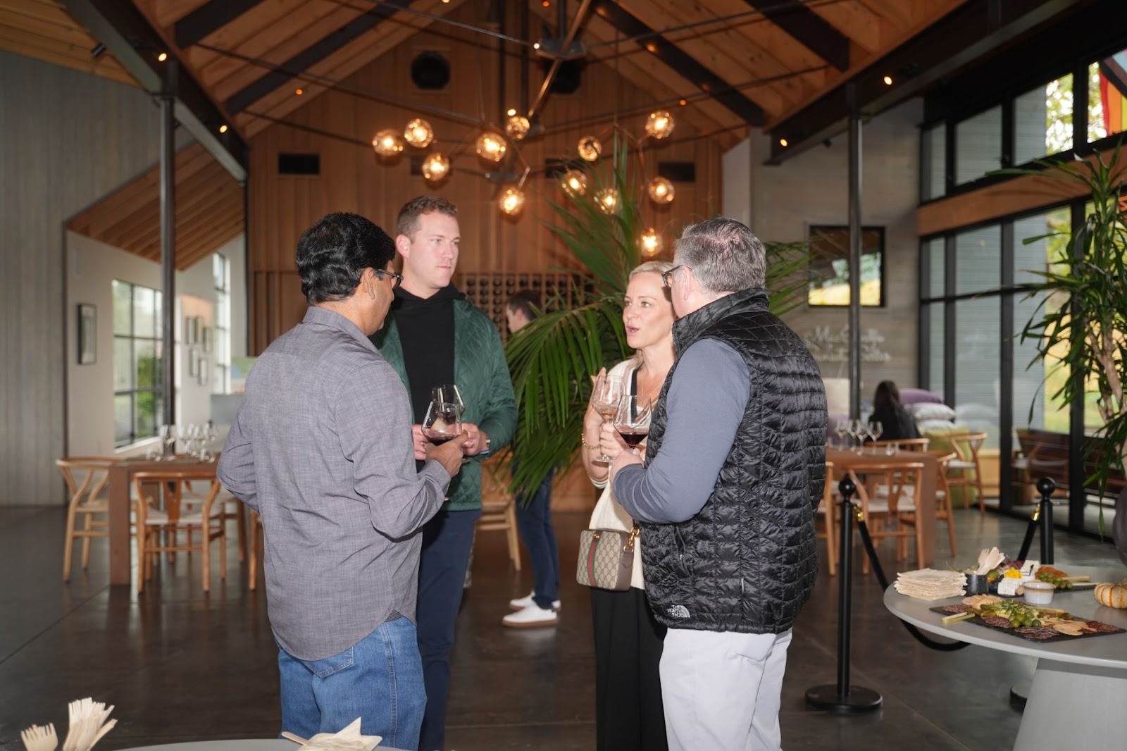 Small group of attendees networking indoors with wine glasses at the Better Together 2025 event in Sonoma, hosted by Zaelab in partnership with ServiceNow and Shopify.
