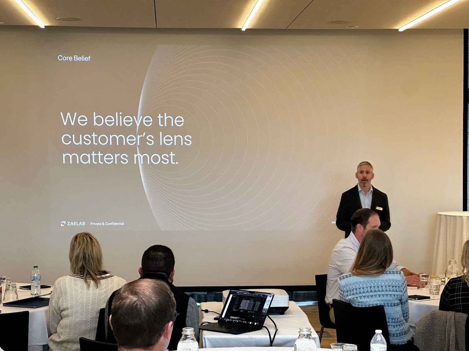 Zaelab CEO Evan Klein presenting in front of a large screen displaying the Zaelab message “We believe the customer’s lens matters most” at the Better Together 2025 event in Sonoma, hosted by Zaelab in partnership with ServiceNow and Shopify.