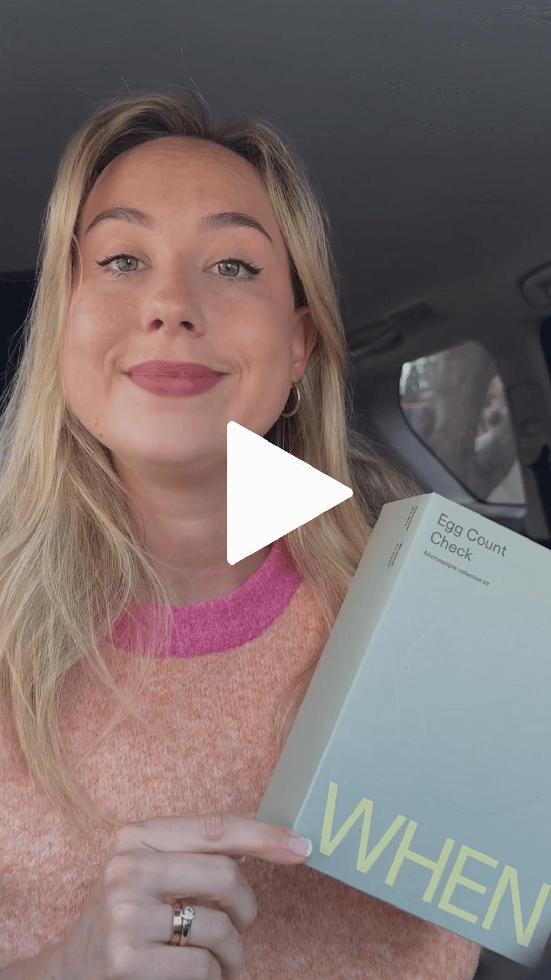 A woman holding a WHEN box, with a play icon to play a video