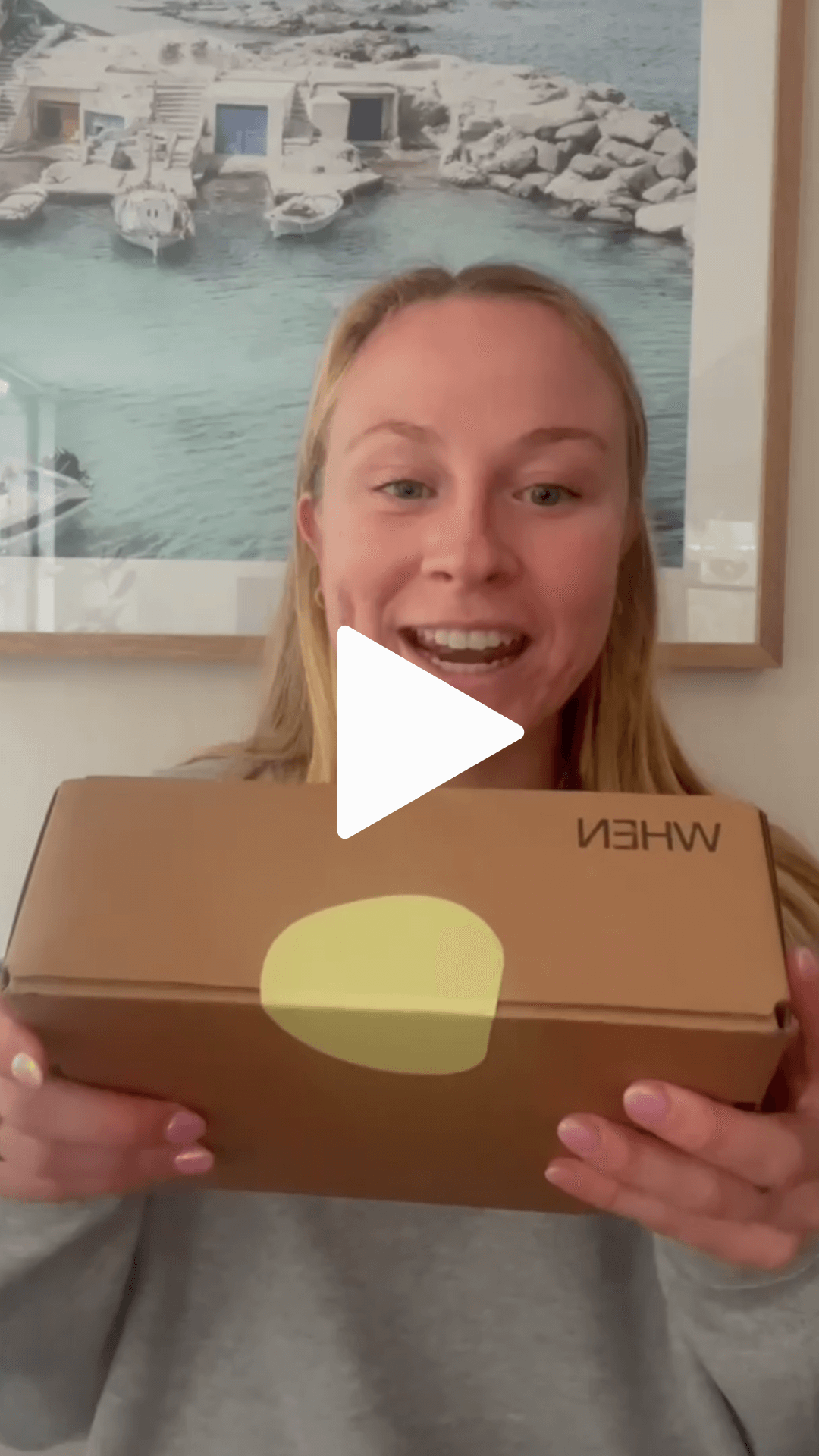 A woman holding a WHEN box, with a play icon to play a video