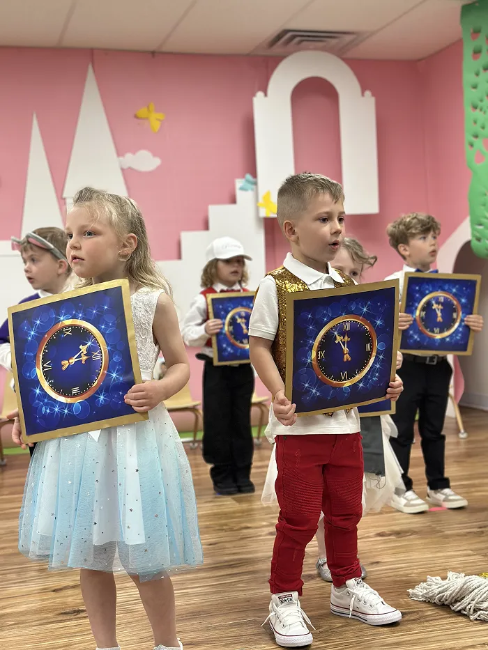 Children dressed in costumes with clock props performing in Children’s Land preschool stage show.