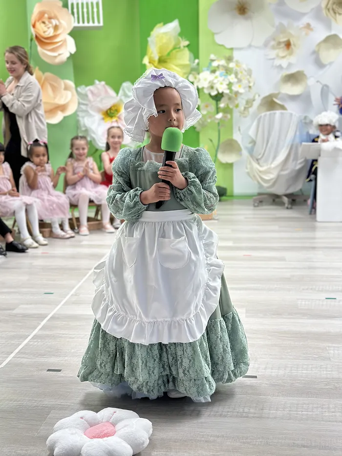 Young girl in white dress performing in preschool Broadway show at Children’s Land.