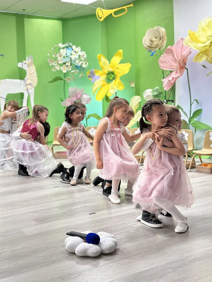 Group of preschool children dressed in pink costumes singing and dancing at Children’s Land show.