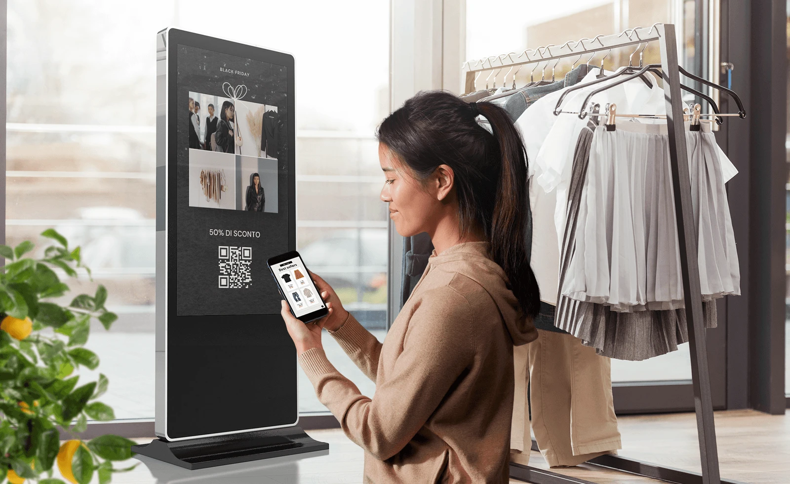 Cliente in negozio retail che confronta una borsa con il display digitale Livesignage che mostra la scheda prodotto con dettagli e caratteristiche