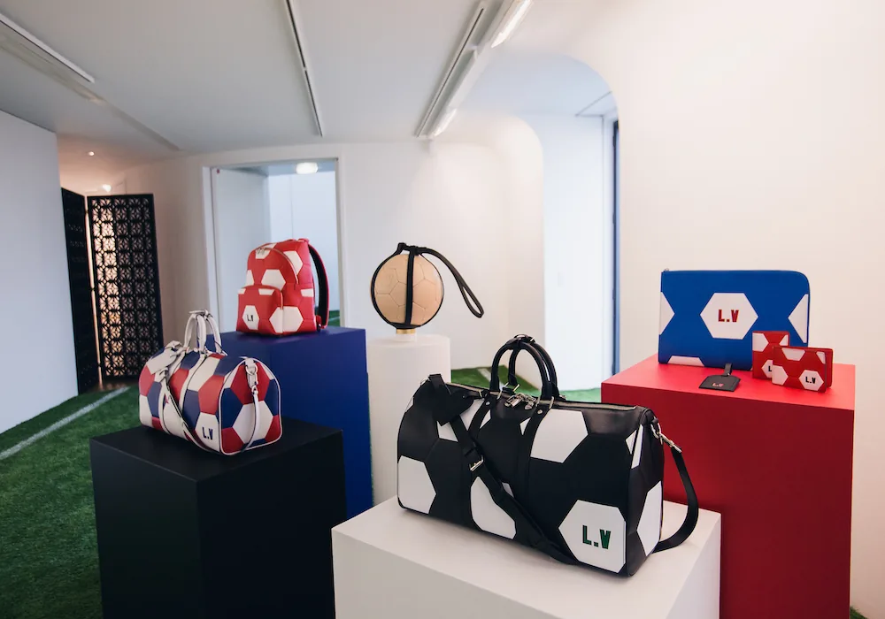 Photo du lancement de la collection Louis Vuitton x FIFA 2018, montrant des ballons dorés et des décorations festives