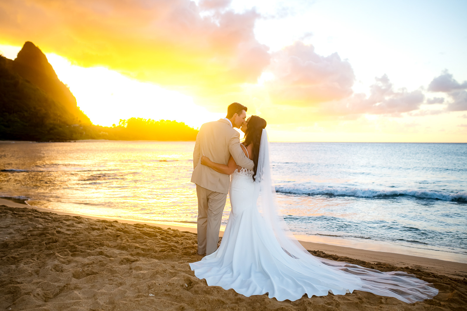 bride and groom kissing on beach in kauai elopement wedding at sunset