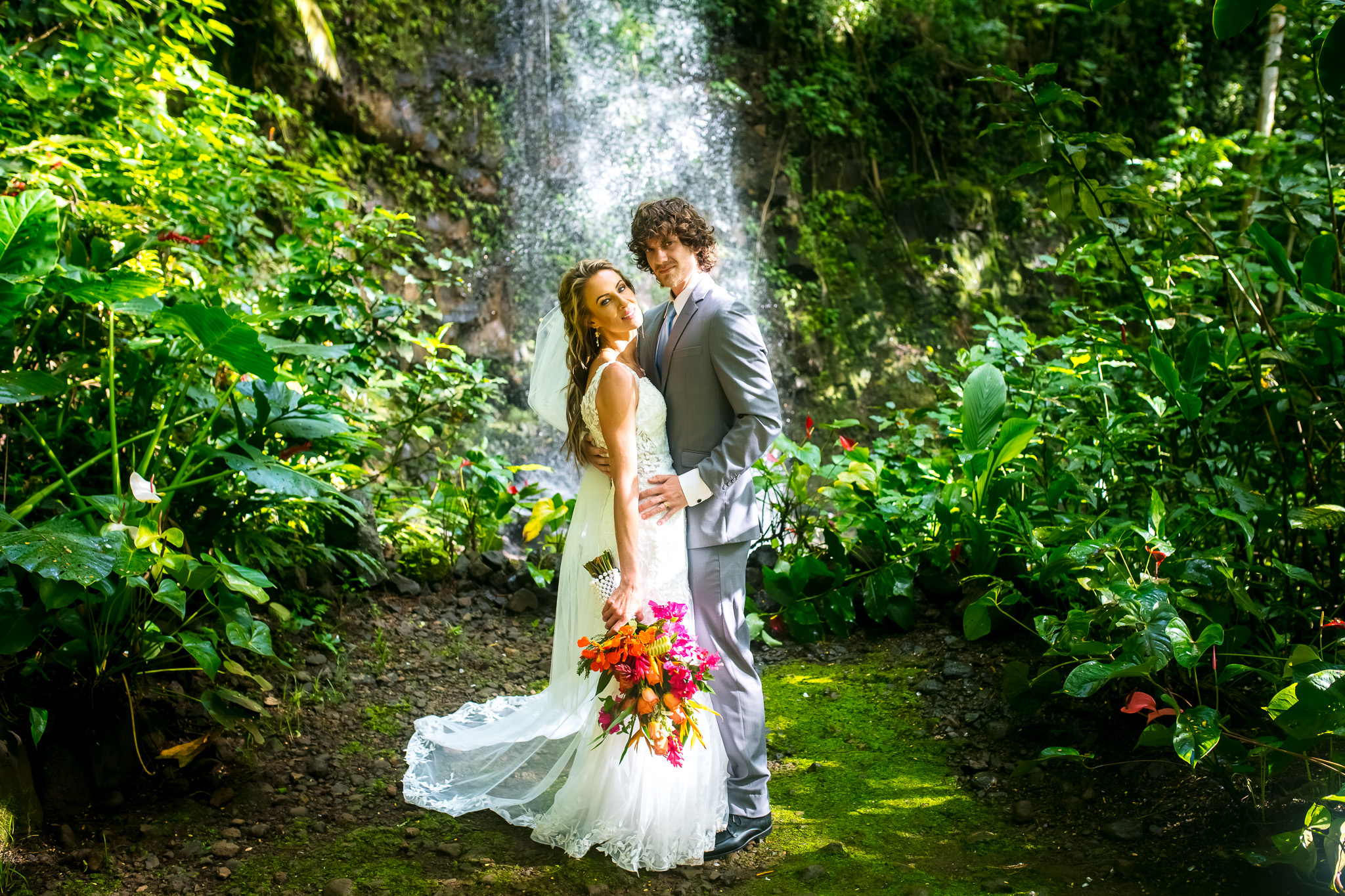 couple posing in front of waterfall kauai