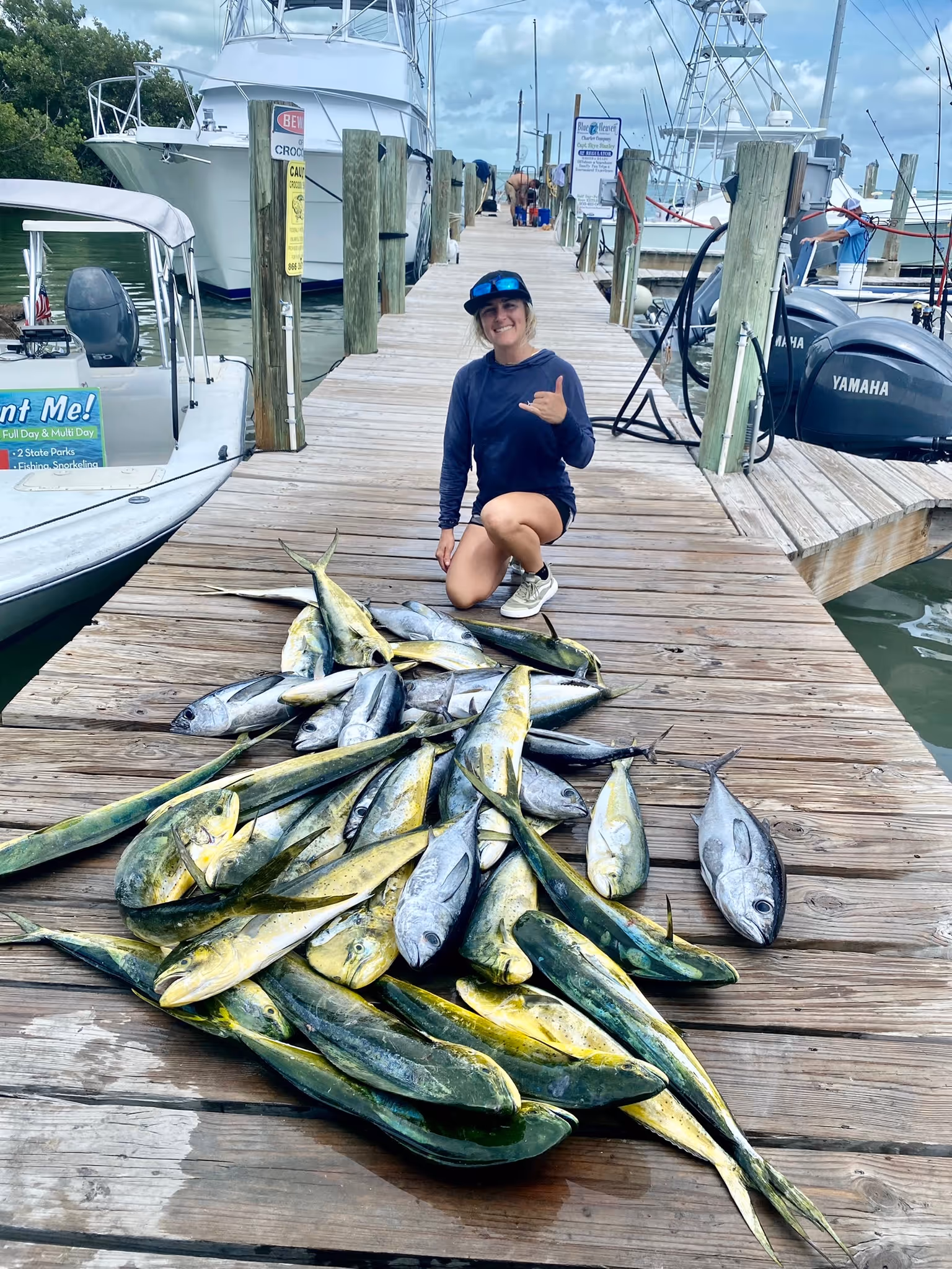 Cailin, owner of Fish to Table, proudly kneels with a several mahi mahi and other fish from a Florida Keys charter.