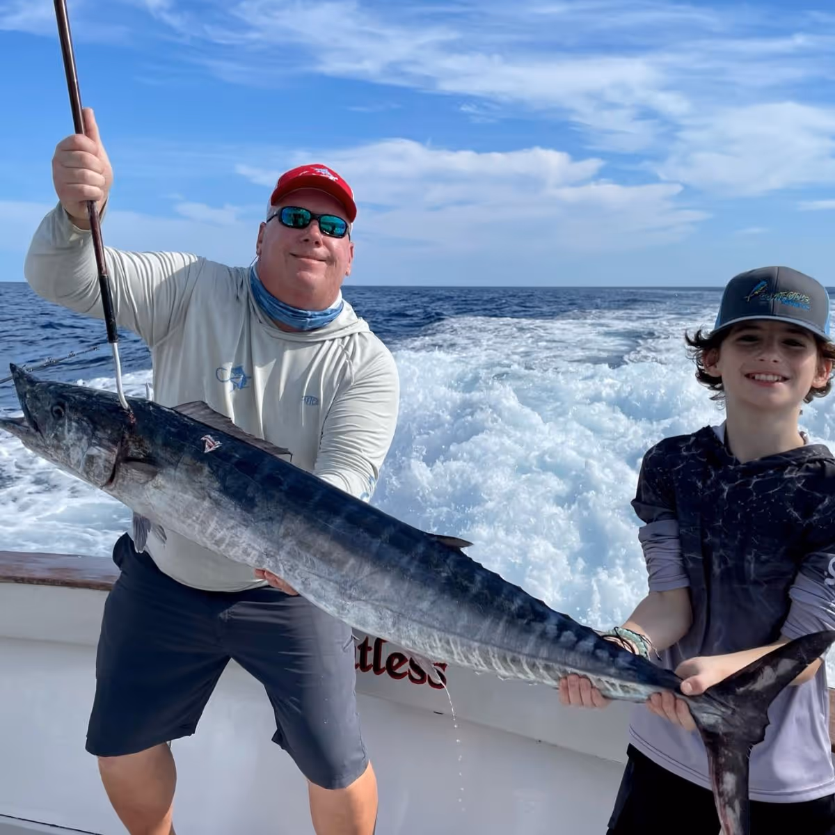 Fish to Table customers holding a wahoo with a gaff on a boat in the Florida Keys.
