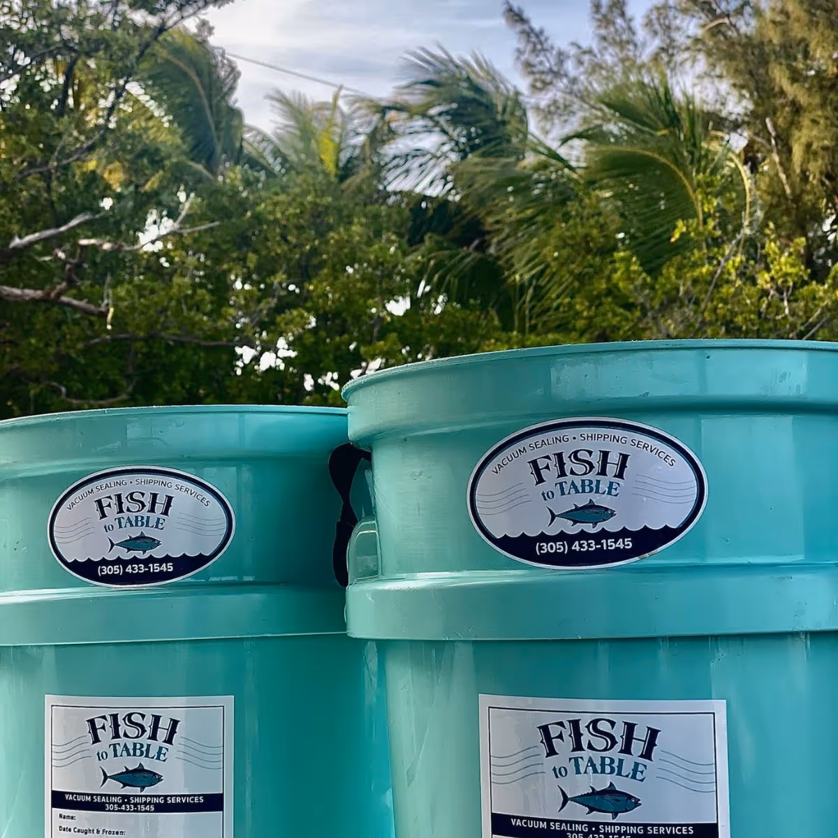 Several stacked blue buckets with Fish to Table stickers on them.