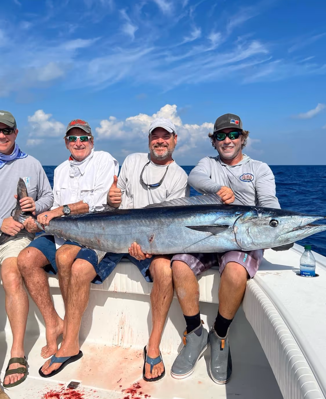 A group of Fish to Table customers holding a very large wahoo on a boat in the Florida Keys.