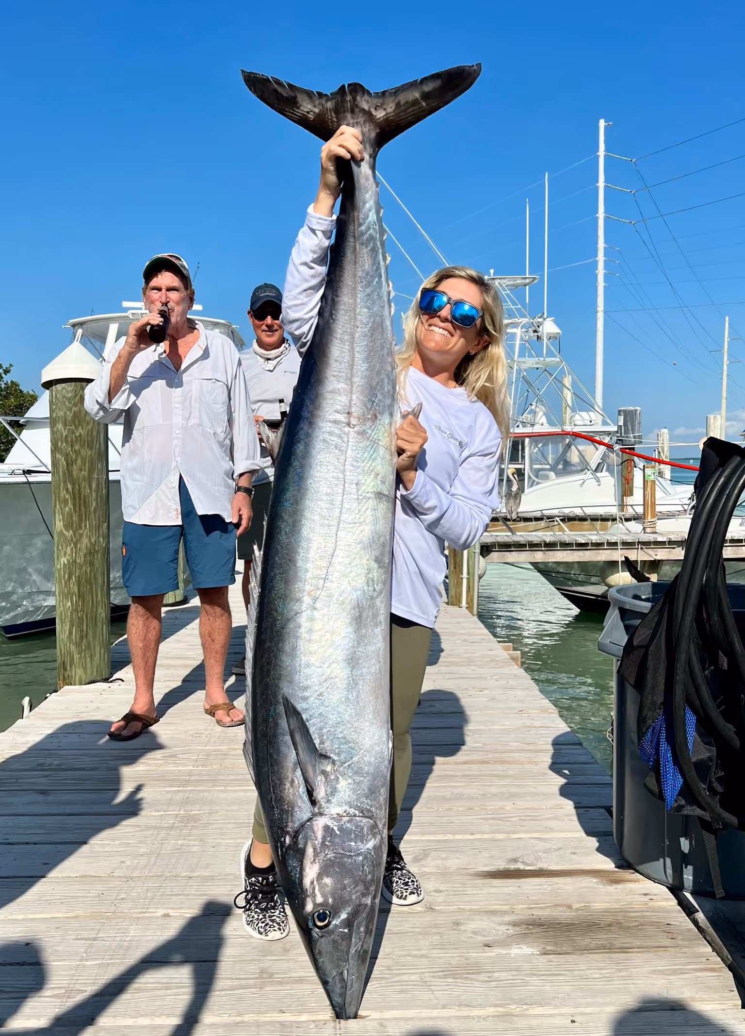 Cailin, owner of Fish to Table holds up a ver large wahoo on the docks of Robbie's Marina in Islamorada.